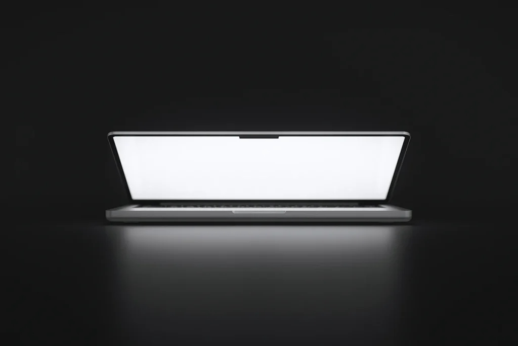 Ordinateur portable ouvert dont l’écran lumineux éclaire une surface sombre