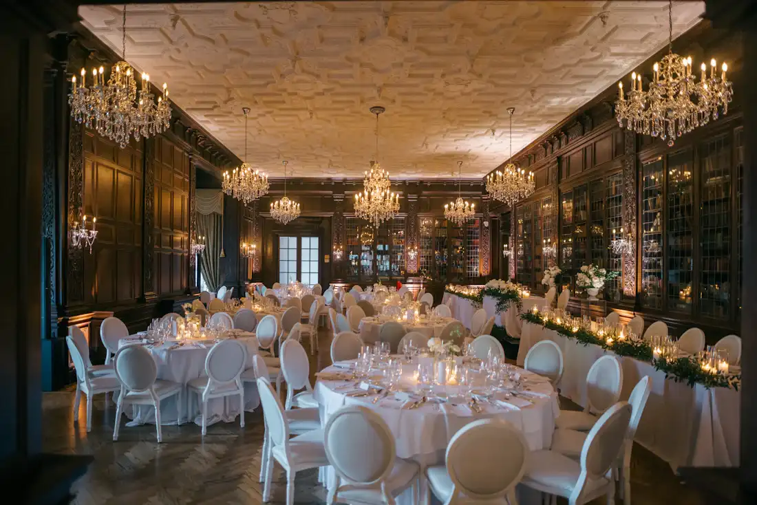 Grande salle de réception avec lustres et tables rondes dressées pour un événement